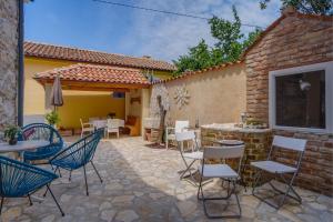 een patio met stoelen en tafels en een gebouw bij Mediterranes Ferienhaus m. Terrasse in Veli Lošinj