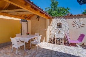 d'une terrasse avec une table, des chaises et une cheminée en pierre. dans l'établissement Mediterranes Ferienhaus m. Terrasse, à Veli Lošinj