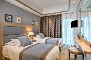 a hotel room with two beds and a desk at Rodos Park in Rhodes Town