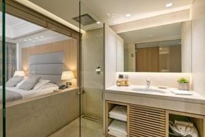 a bathroom with a shower and a sink and a bed at Rodos Park in Rhodes Town
