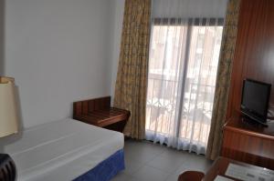 a bedroom with a bed and a tv and a window at Hostal Vila del Mar in Lloret de Mar