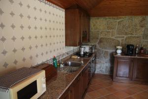 una cocina con fregadero y microondas en casa das pombas, en Barcelos