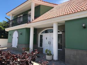 特爾德的住宿－Chalet Canarias，绿色的房子,设有白色的门和阳台