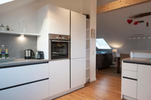 cocina con armarios blancos y encimera en Ferienwohnung Stern, en Friedenweiler