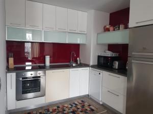 a kitchen with white cabinets and silver appliances at Apartment Poiana Brasov in Poiana Brasov