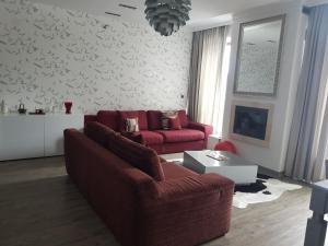 uma sala de estar com um sofá vermelho e uma televisão em Apartment Poiana Brasov em Poiana Brasov