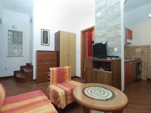 uma sala de estar com uma cadeira, uma mesa e uma televisão em Apartments P-Lena 1775 em Medulin