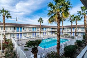 Un edificio de apartamentos con piscina y palmeras. en Motel 6-El Centro, CA, en El Centro