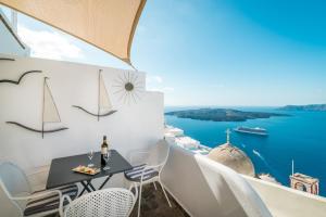 balcone con tavolo, sedie e vista sull'oceano di Angel Luxury Suites a Firà