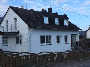 a white house with a black roof and a wooden fence at Zur Burgmauer in Welschbillig
