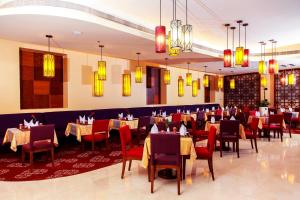 uma sala de jantar com mesas, cadeiras e lustres em Grand Regal Hotel em Doha