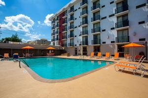 una piscina frente a un hotel con sillas y sombrillas en Motel 6-Atlanta, GA - Atlanta Airport, en Atlanta