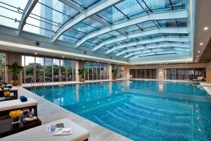 an indoor pool with a glass ceiling and a large swimming pool at Ascott IFC Guangzhou - Free Shuttle Bus For Canton Fair in Guangzhou