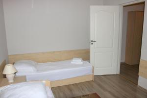 a white bedroom with a bed and a door at Dom Litewski in Sejny