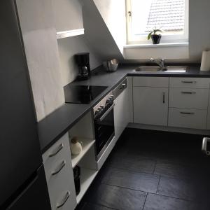 a kitchen with white cabinets and a black counter top at Zur Burgmauer in Welschbillig