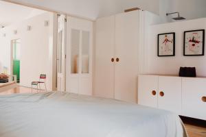 a white bedroom with a bed and white cabinets at La Casona Beach House in Valencia