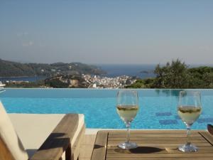 dwa kieliszki białego wina siedzące na stole przy basenie w obiekcie Skiathos Garden Cottages w mieście Skiatos