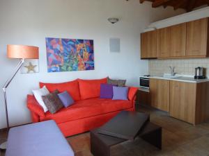 a living room with a red couch and a kitchen at Skiathos Garden Cottages in Skiathos Town