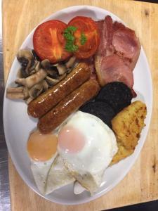 a plate of breakfast food with eggs sausage and mushrooms at White Heather Guest House in Mablethorpe