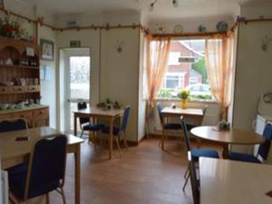 a dining room with tables and chairs and a window at White Heather Guest House in Mablethorpe