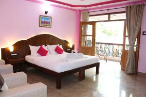 a bedroom with a bed with pink walls at Sea View Resort in Patnem +43 photos