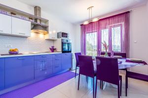 a kitchen with purple cabinets and a table with chairs at Apartman - The view in Krk