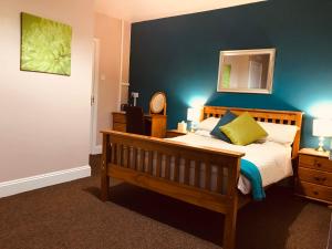 a bedroom with a bed with a blue wall at White Heather Guest House in Mablethorpe