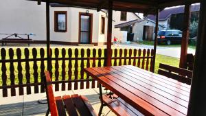 een houten picknicktafel op een veranda met een hek bij Agroturystyka u Tadka in Klęczany