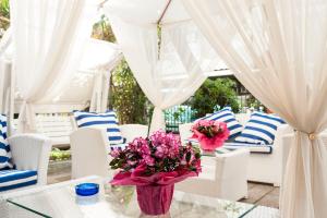 Hotel Capinera في ريميني: مزهرية من الزهور على طاولة زجاجية مع كراسي بيضاء