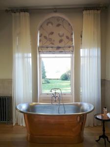 uma grande banheira de madeira num quarto com uma janela em Cleatham Hall em Manton