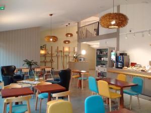 a restaurant with tables and chairs and a kitchen at HALT HOTEL - Choisissez l'Hôtellerie Indépendante in Lattes