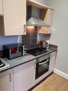 een keuken met een fornuis oven naast een magnetron bij Central Matlock Apartment in Matlock