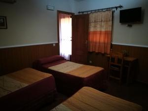 Habitación pequeña con 2 camas y ventana en Hostal Hueso en Trujillo