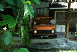 un jeep naranja está sentado en algunos escalones en Losmanos Hostel en Yogyakarta