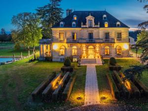 a large house with lights on in the yard at Garrigae Manoir de Beauvoir Poitiers Sud - Hotel & Spa in Mignaloux-Beauvoir