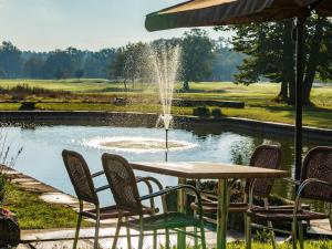a table and chairs in front of a pond with a fountain at Garrigae Manoir de Beauvoir Poitiers Sud - Hotel & Spa in Mignaloux-Beauvoir +57 photos
