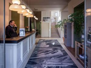 a man sitting at a counter in a room with a marble floor at Garrigae Manoir de Beauvoir Poitiers Sud - Hotel & Spa in Mignaloux-Beauvoir