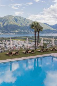 a large pool of water surrounded by palm trees at Villa Orselina - Small Luxury Hotel in Locarno
