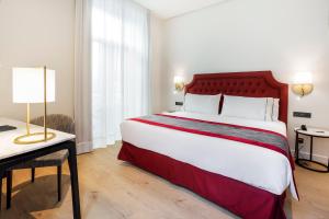 a hotel room with a bed, table and a lamp at Eurostars Azahar in Córdoba