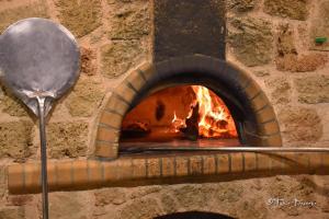 a brick oven with a spoon and a fire at 24 Seven Boutique Hotel in Malia