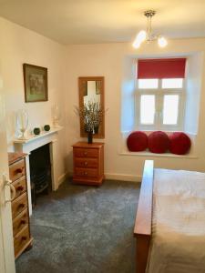 1 dormitorio con cama y ventana con almohadas rojas en Coniston Cottage Lake View en Coniston