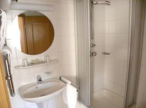 La salle de bains est pourvue d'un lavabo et d'une douche avec un miroir. dans l'établissement Hotel Restaurant Adler Bühlertal, à Bühlertal