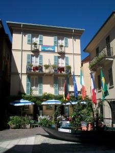 a building with flags and umbrellas in front of it at Albergo Il Vapore in Menaggio