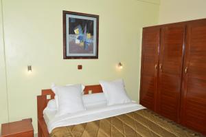 - une chambre avec un grand lit et des oreillers blancs dans l'établissement Hotel - Y, à Douala