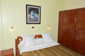 a bedroom with a large bed with white pillows at Hotel - Y in Douala