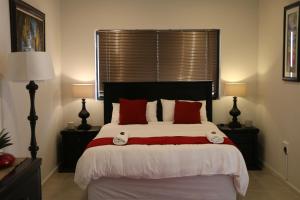 a bedroom with a large bed with red pillows at Millennium Body Guards Guesthouse in Hartbeespoort