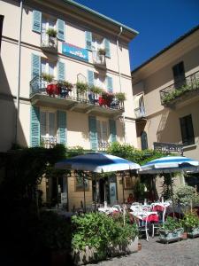an outdoor cafe with tables and umbrellas in front of a building at Albergo Il Vapore in Menaggio