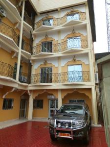un coche aparcado frente a un edificio en Hotel - Y en Douala