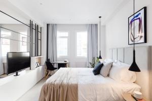 a white bedroom with a bed and a flat screen tv at Luxury Apartments in Plaka by UPSTREET in Athens