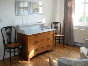 a bathroom with a wooden dresser with a sink and two chairs at Villa Monique in Alt-Sassnitz in Sassnitz